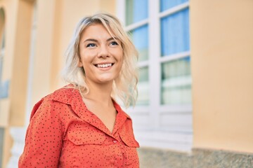 Young blonde woman smiling happy walking at the city.