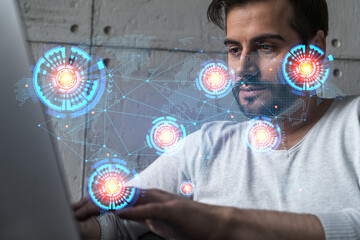 A serious caucasian manager in casual wears, using laptop to develop a new worldwide supply chain. Double exposure. globe and map hologram.