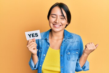 Beautiful young woman with short hair holding yes reminder screaming proud, celebrating victory and...