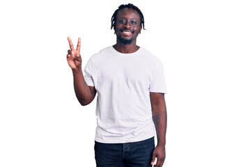 Fototapeta premium Young african american man with braids wearing casual white tshirt showing and pointing up with fingers number two while smiling confident and happy.