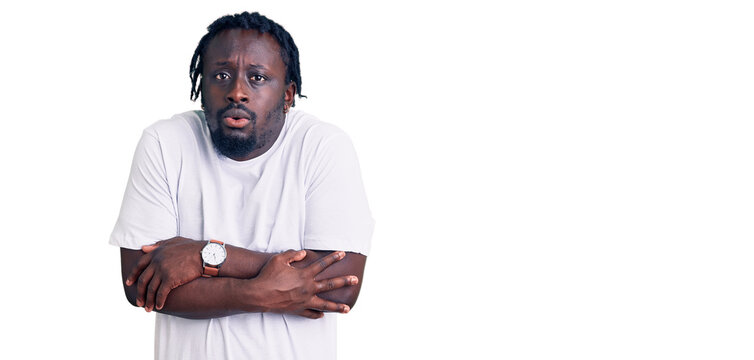 Young african american man with braids wearing casual white tshirt shaking and freezing for winter cold with sad and shock expression on face