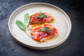 Modern Style traditionelle italienische gebratene Schnitzel saltimbocca alla Romana vom Kalb mit Parma Schinken und Salbei Blätter angeboten als close-up auf einem Nordic Design Teller