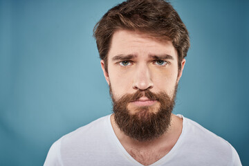Obraz premium Bearded man displeased facial expression emotions close-up blue background white t-shirt