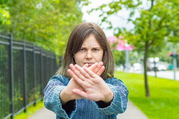 A young girl stretches her hand forward with an open palm as a STOP sign. The concept is irritation and aggression, an attempt to stop or prohibit something.