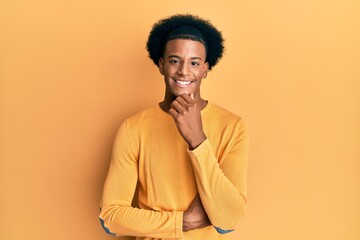 African american man with afro hair wearing casual clothes smiling looking confident at the camera with crossed arms and hand on chin. thinking positive.
