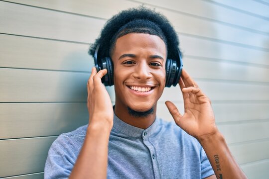 Young african american man listening to music using headphones at the city.