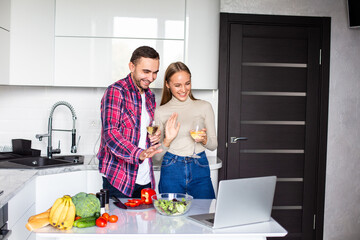 Video call. Nice pleasant couple with glass of wine sitting in front of the laptop while calling to their relatives