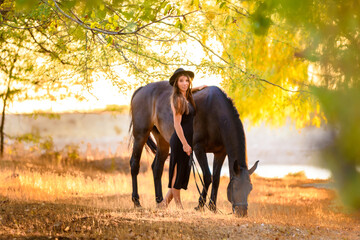 Fototapeta premium Girl walks in the forest with a horse at sunset