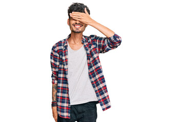 Young hispanic man wearing casual clothes smiling and laughing with hand on face covering eyes for surprise. blind concept.