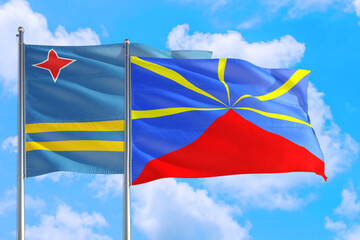 Reunion and Aruba national flag waving in the windy deep blue sky. Diplomacy and international relations concept.