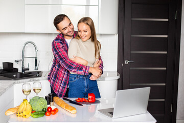 Portrait of young couple cooking together in the kitchen at home.