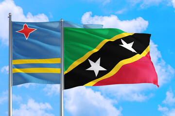 Saint Kitts And Nevis and Aruba national flag waving in the windy deep blue sky. Diplomacy and international relations concept.