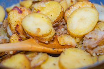 Hot baked potato slices with thin skinned potatoes on a plate. A piece of potatoes on a fork. A simple and quick after-work meal for the worker and bachelor. Inexpensive food