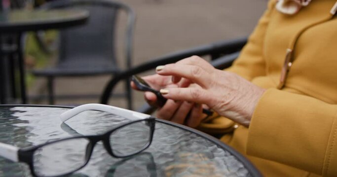 Close-up of glasses lying on the table in the background female hands using phone on social network