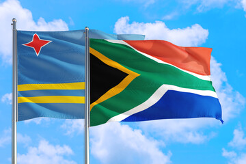 South Africa and Aruba national flag waving in the windy deep blue sky. Diplomacy and international relations concept.