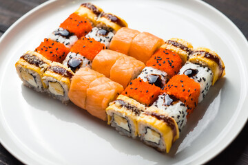 set of various sushi on white plate on wooden table background. Rolls of philadelphia and other.