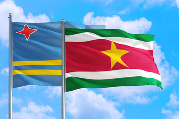 Suriname and Aruba national flag waving in the windy deep blue sky. Diplomacy and international relations concept.