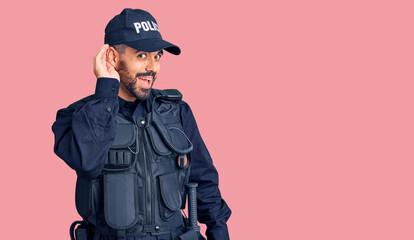 Young hispanic man wearing police uniform smiling with hand over ear listening an hearing to rumor or gossip. deafness concept.