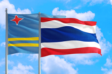 Thailand and Aruba national flag waving in the windy deep blue sky. Diplomacy and international relations concept.