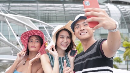 Three asian friends strolling in the city taking selfies. Happiness and tourism concept
