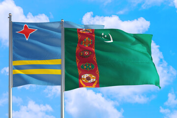 Turkmenistan and Aruba national flag waving in the windy deep blue sky. Diplomacy and international relations concept.