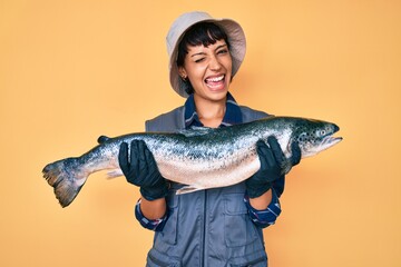 Beautiful brunettte fisher woman showing raw salmon winking looking at the camera with sexy...