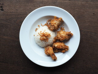 Top view dish of steamed rice with deep-fried garlic and chicken wings on wooden table