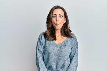 Obraz premium Young brunette woman wearing casual winter sweater making fish face with lips, crazy and comical gesture. funny expression.