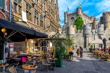Old street with tables of cafe in Ghent (Gent), Belgium. Architecture and landmark of Ghent. Cozy cityscape of Ghent. - obrazy, fototapety, plakaty