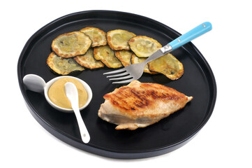 Escalope de poulet servie avec des rondelles de courgettes dans une assiette sur fond blanc