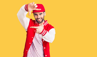 Young handsome man with beard wearing baseball jacket and cap smiling making frame with hands and fingers with happy face. creativity and photography concept.