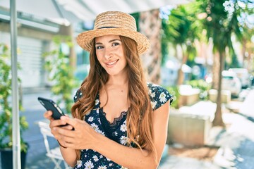 Young hispanic woman on vacation using smartphone at street of city.