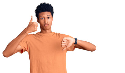 Young african american man wearing casual clothes doing thumbs up and down, disagreement and agreement expression. crazy conflict