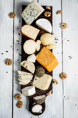 Various types of cheese. On a white wooden background. Blue cheeses with spices. Around honey and walnuts. Home cheese dairy. view from above