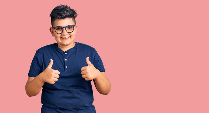 Little boy kid wearing casual clothes and glasses success sign doing positive gesture with hand, thumbs up smiling and happy. cheerful expression and winner gesture.