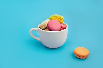 French multicolored macaroons in a white teacup. Dessert.