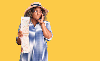 Young african american plus size woman wearing summer hat holding city map serious face thinking about question with hand on chin, thoughtful about confusing idea