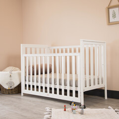 Modern baby room interior with a cozy classic crib and miniature toys placed on a soft carpet