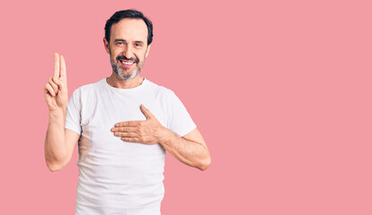Middle age handsome man wearing casual t-shirt smiling swearing with hand on chest and fingers up,...