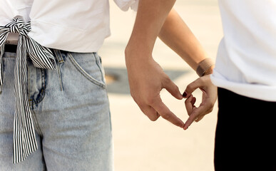 Couple, guy and girl hold each other's hands, fingers form a heart