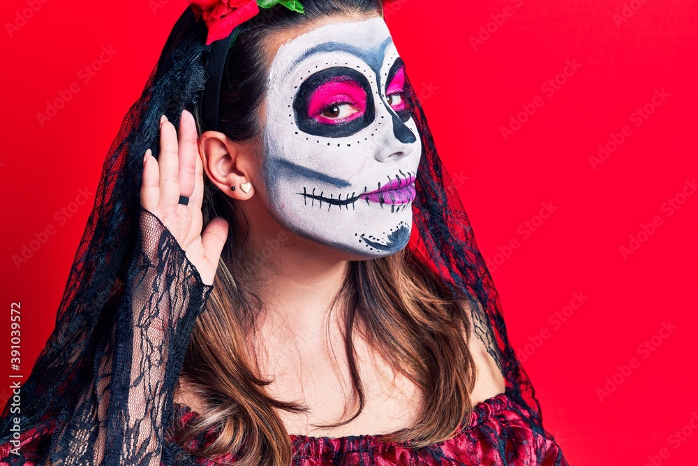 Sticker Young woman wearing day of the dead costume over red smiling with hand over ear listening and hearing to rumor or gossip. deafness concept.