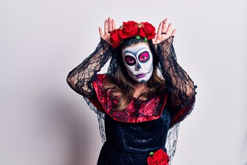 Young woman wearing day of the dead costume over white doing bunny ears gesture with hands palms looking cynical and skeptical. easter rabbit concept.