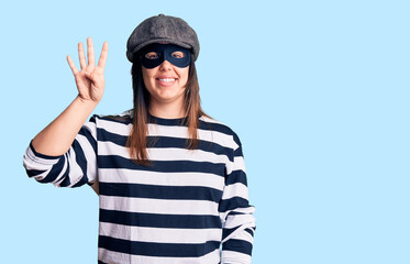Young beautiful brunette woman wearing burglar mask showing and pointing up with fingers number four while smiling confident and happy.