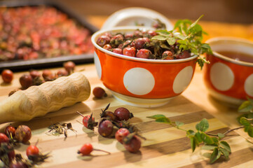 Harvest of juicy rose hips on a baking sheet and rose hip tea close-up.