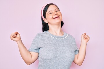 Brunette woman with down syndrome wearing casual clothes very happy and excited doing winner...