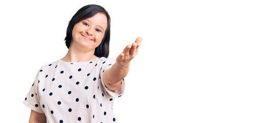 Brunette woman with down syndrome wearing casual clothes smiling friendly offering handshake as greeting and welcoming. successful business.