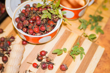 Harvest of juicy rose hips on a baking sheet and rose hip tea close-up.