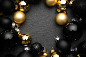 Noel design. Golden New Year balls, black baubles in xmas composition on dark textured background for greeting card. Flat lay, top view, copy space.