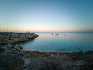 Cristal clear water and no people at the famous Cala Azzurra in Favignana, Italy. A perfect calm sunrise in this paradise island in the mediterranean sea
