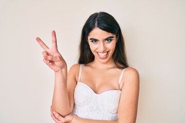 Brunette teenager girl posing elegant smiling with happy face winking at the camera doing victory sign. number two.
